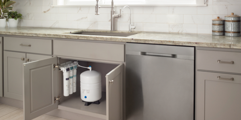 Brondell Capella Reverse Osmosis Under Sink Water Filtration System installed under sink in grey cabinets and white modern accent tiles.